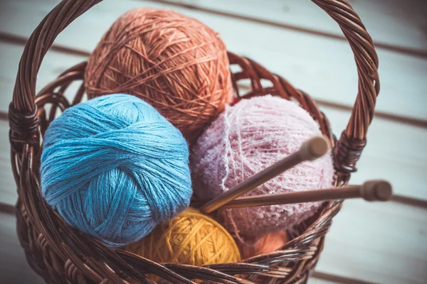 Background of basket with colorful balls of yarn with knitting needles