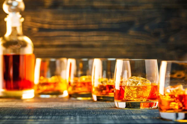 Shot glasses of scotch whiskey on a wooden background, selective