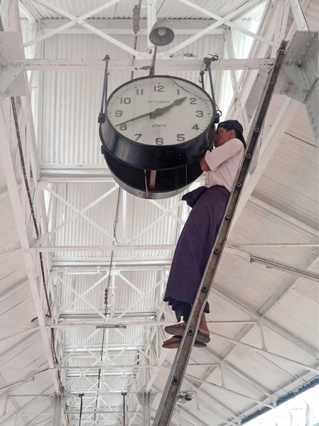 Burmese Man setting time on a big clock in (Rangoon) Yangon, (Burma) Myanmar