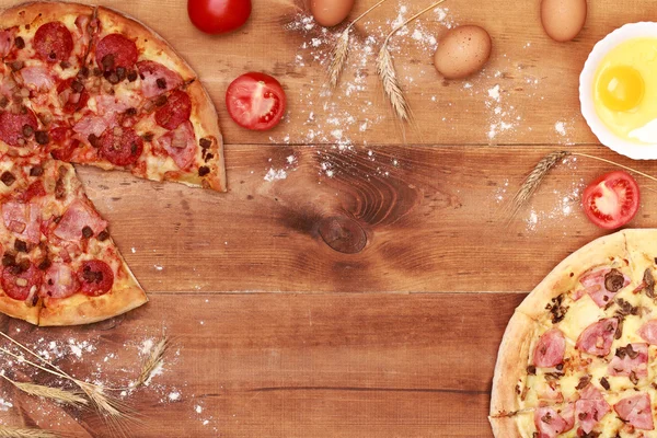 Two tasty pizzas on a wooden background