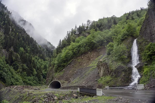 Landscape with a highway, mountain tunnel and a waterfall