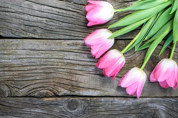 Fresh pink tulip flowers on wooden table. Top view with copy space. Valentine\'s day rose tulips over wooden background.