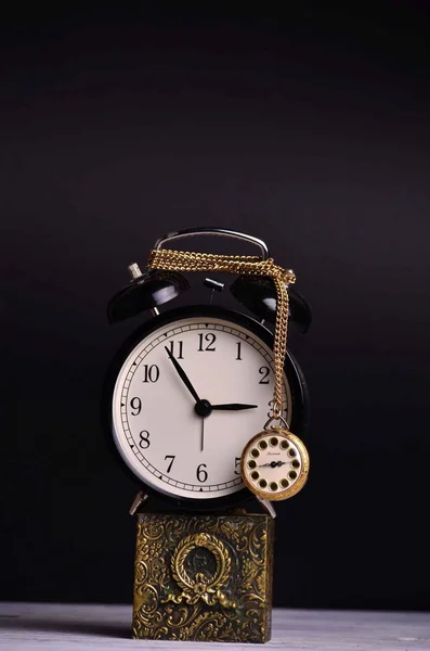 Pocket watch hanging on alarm clock