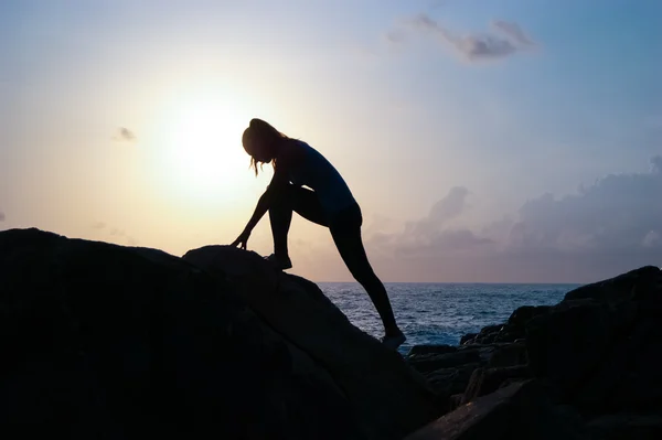 The young beautiful girl the sportswoman, in sportswear sneakers jumps through rocks at sunset, a high jump, physical training, fitness the instructor, an extreme sport, parkour,