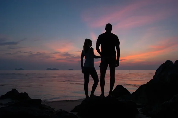 Young couple watch a decline, the Guy with the girl stand on the seashore and look in a distance,