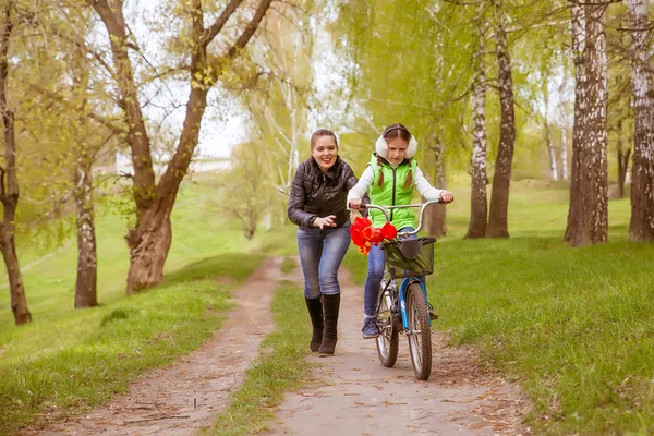 Happy mother teaches his daughter to ride a bike. A mother is glad to successes of daughter