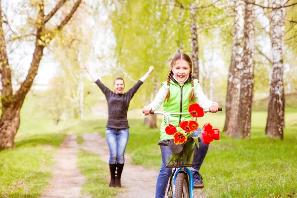 Happy mother teaches his daughter to ride a bike. A mother is glad to successes of daughter