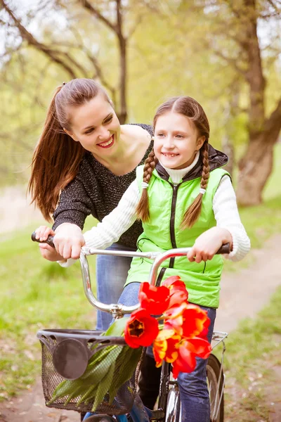 Happy mother teaches his daughter to ride a bike. A mother is glad to successes of daughter