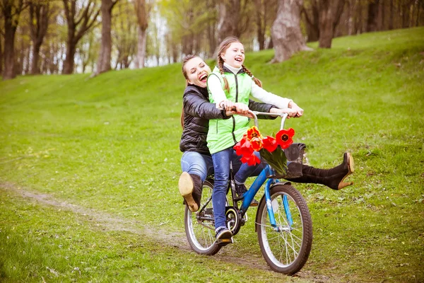 The daughter takes her mother on a Bicycle on the lake in the Park . They\'re having fun.