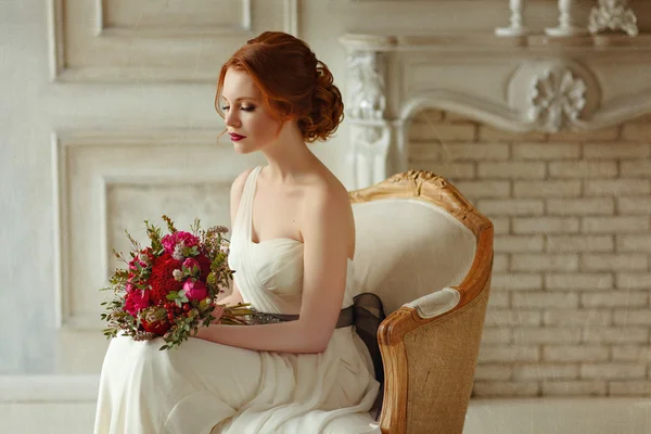 Very pretty sophisticated red-haired girl sitting in a chair wit
