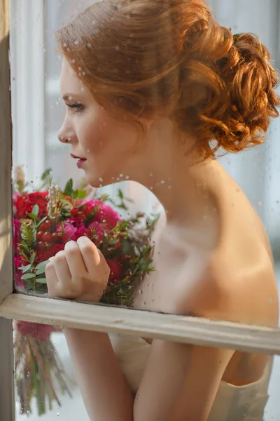 Very pretty sophisticated red-haired girl with a bouquet in his