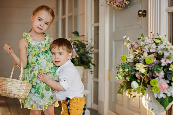 Sister in a green dress and her younger brother, are embracing i