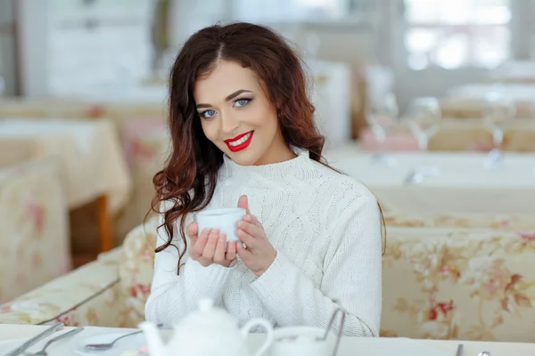 Beautiful sexy brunette girl with red lipstick in a white sweate