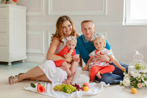 Family - mother, father and two daughters in bright clothes sitt