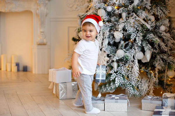 Small charming baby boy in Santa hat and light-colored clothing