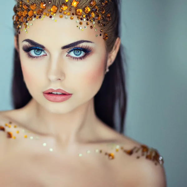 Portrait of a glamorous very beautiful girl brunette with sequins on the face, close up