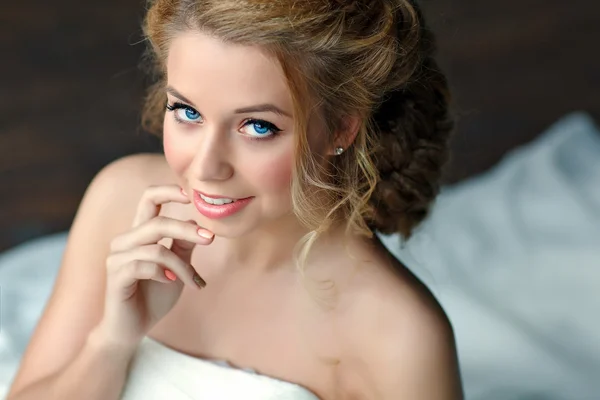 Portrait of a girl with thick blond hair and blue eyes in a  white dress, close-up