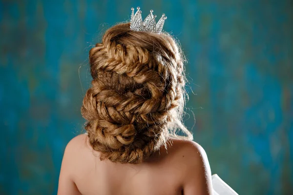 Portrait of a young blonde woman with luxury thick hair, braided into a braid, wearing a white dress and a crown on her head, like a princess, view from the back