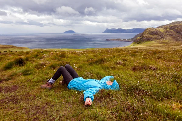 The girl in the blue jacket lying on the grass on a background o