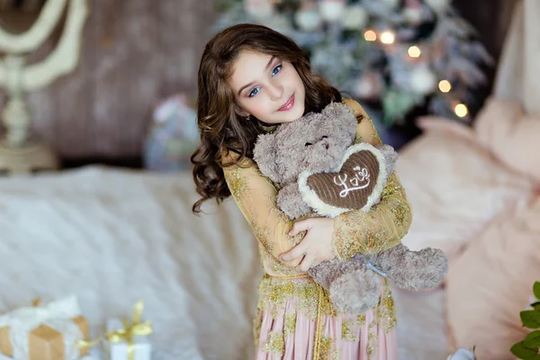 Beautiful young girl holding a Teddy bear and smiling in the bac