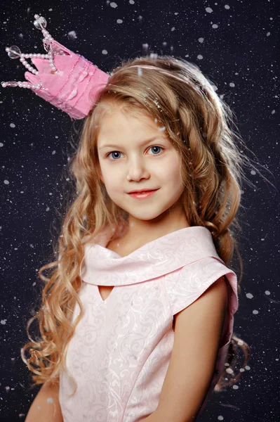 Portrait of a beautiful girl in a pink princess crown on dark ba