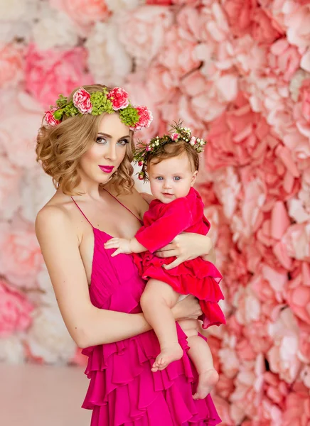 Beautiful slim blonde mom in red dress and a wreath of flowers i