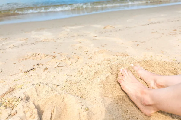 Man and woman\'s feet on a sunny beach sand by the ocean. Copy sp
