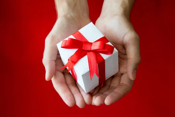 The man hands holding white gift box with red ribbon