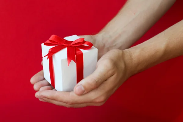 The man hands holding white gift box with red ribbon
