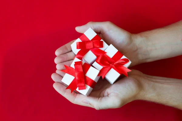 The man hands holding white gifts boxes with red ribbon