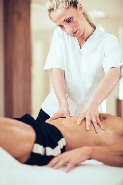 Physical therapyst massaging sportsman