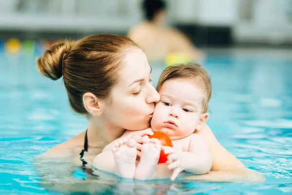 Mother kissing baby in pool