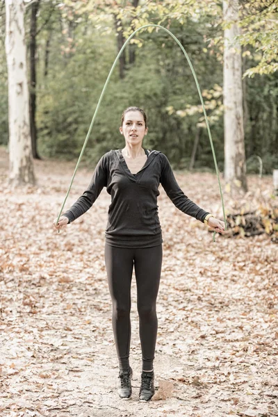 Woman jumping rope in forest