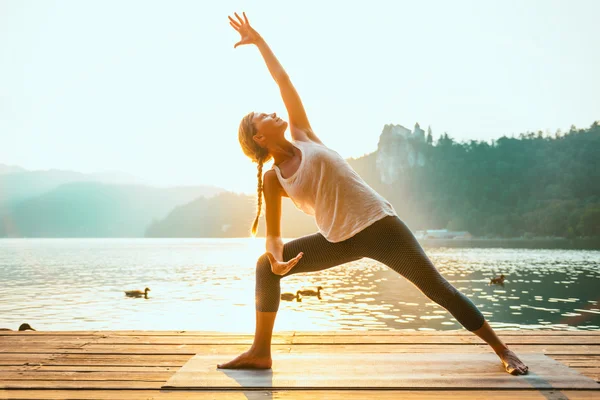 Woman practicing Yoga  by lake