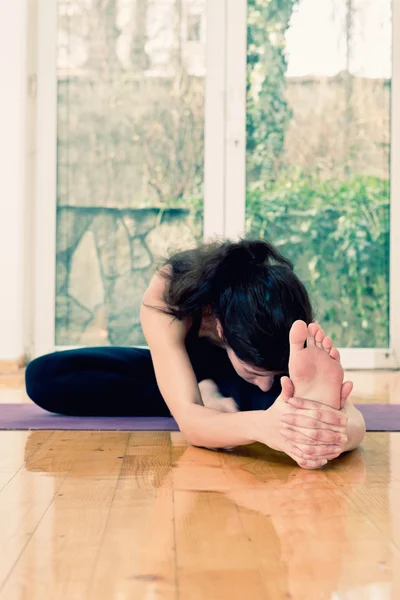 Woman stretching head to knee