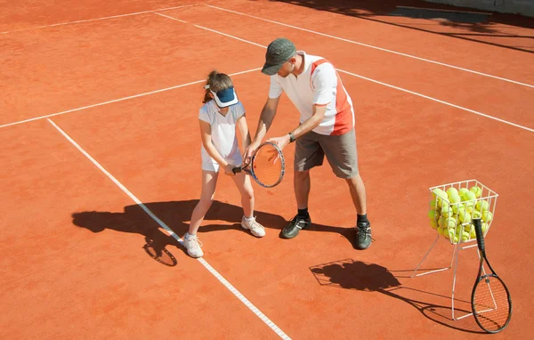coach with  girl on tennis court