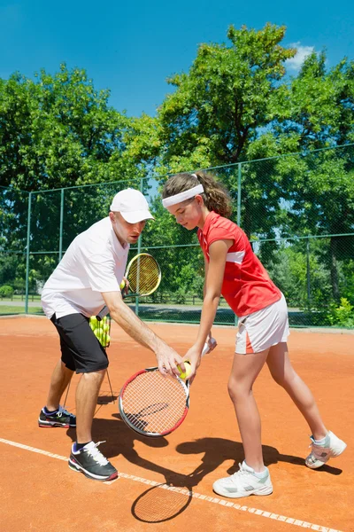 Tennis instructor working with junior player