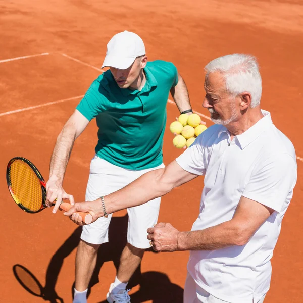 Senior man with tennis instructor