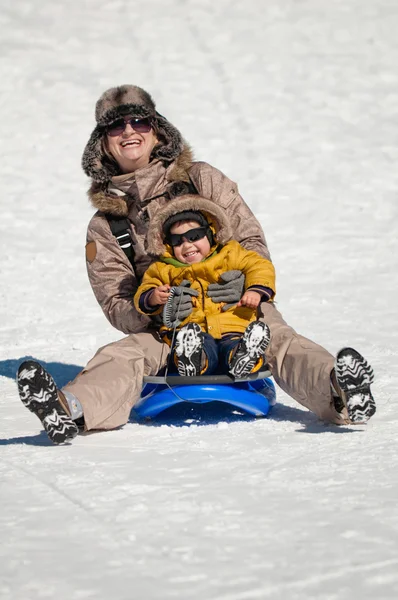 Mother and son enjoying snow sledging