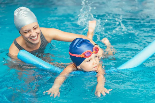 Little girl learning to swim with instructor