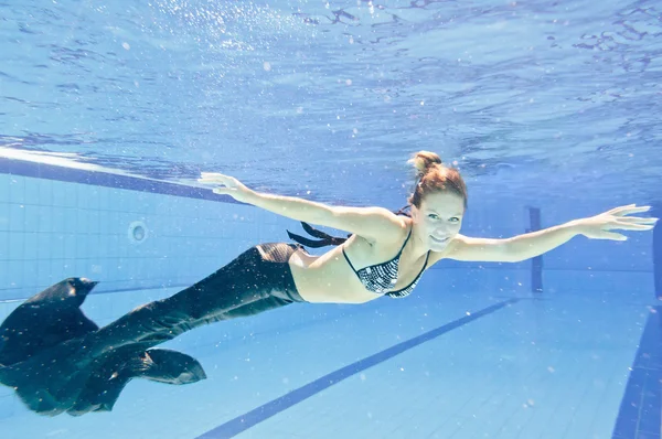 Woman in mermaid costume swimming in pool