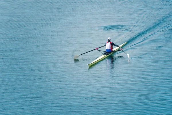 Man rowing single scull on lake
