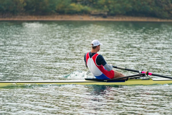 Sportsman rowing single scull on lake
