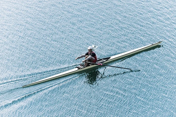 Man rowing single scull on lake