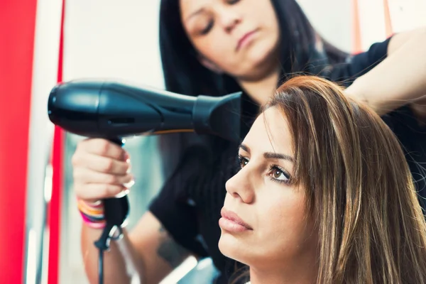Hairdresser drying woman\'s long hair