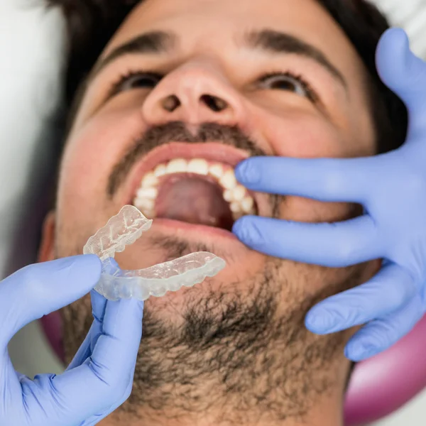 Placing transparent dental braces to patient