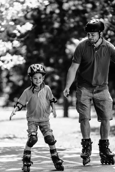 Father teaching son roller skating in park