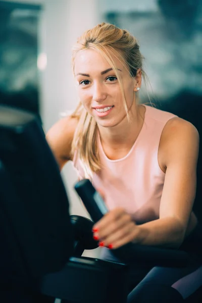 Blond woman using gym bicycle