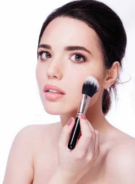 Closeup portrait of a woman  applying dry cosmetic  using makeup brush.