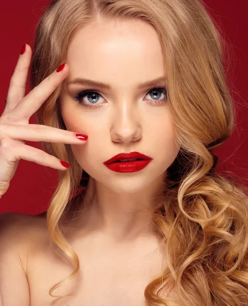 Beautiful face of a fashion model with blue eyes.Curly hair. Red lips. Studio portrait.